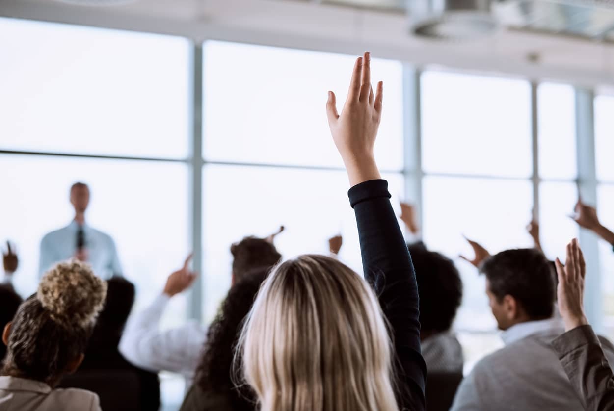 group of students raising their hands to ask questions during a class