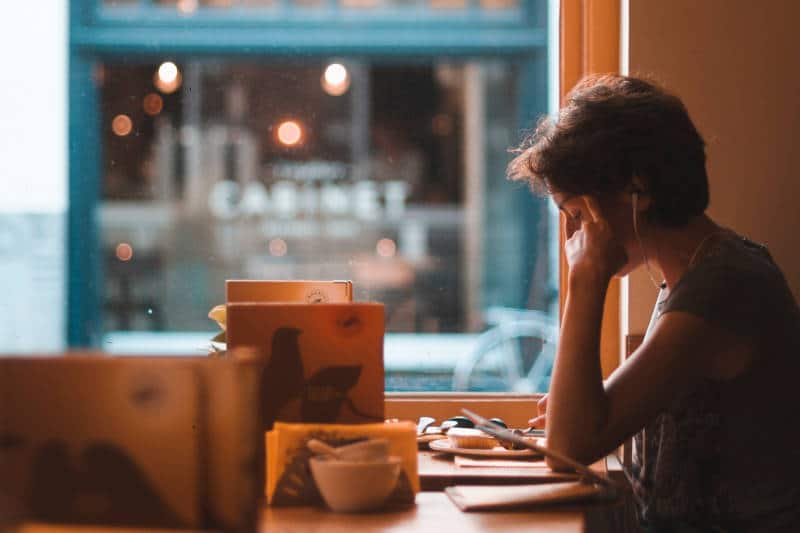 female at restaurant listening to soothing sounds to deal with school related stress