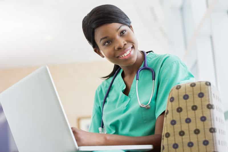 image of a female biosciences pre-med student looking to a side and smiling while working with a laptop computer