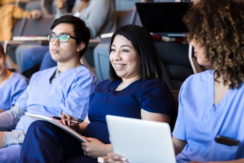 multi-ethnic group of nursing students sit in the lecutre hall on campus