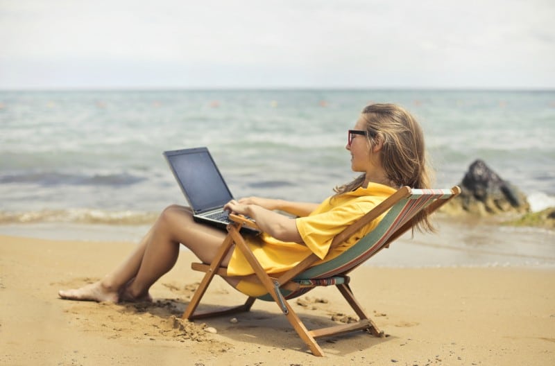 woman researching post bacc programs via laptop on the beach young woman using laptop computer on the beach to do her pre-med studies