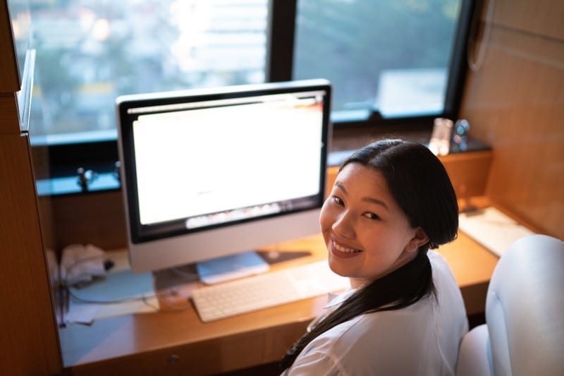 post bacc medical student learning online asian medical student smiling while attending pre med classes on desktop computer