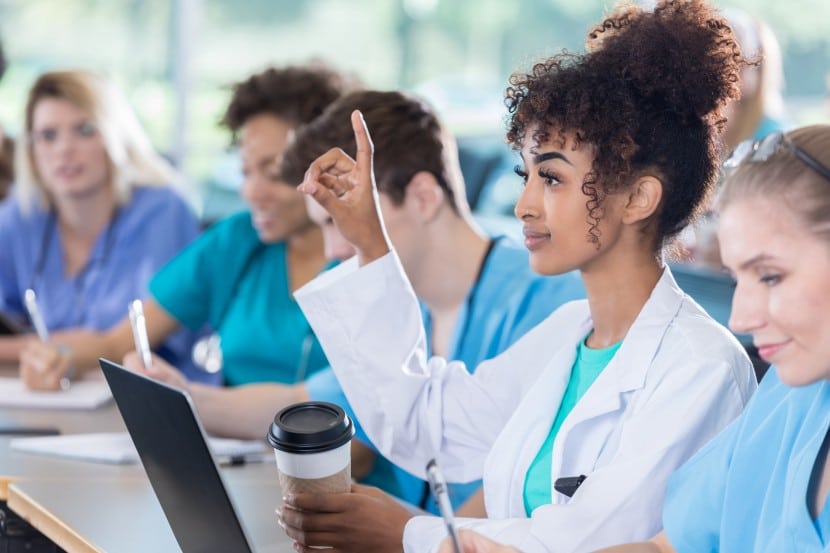 pre-med students preparing for MCAT exam african american female raising hand with a question in classroom with pre-med students