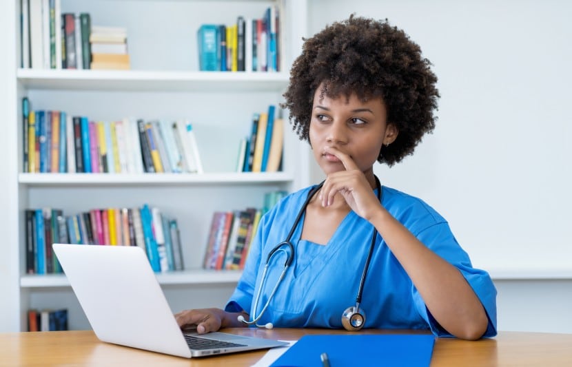 Thinking afro american nurse or medical student at computer at hospital